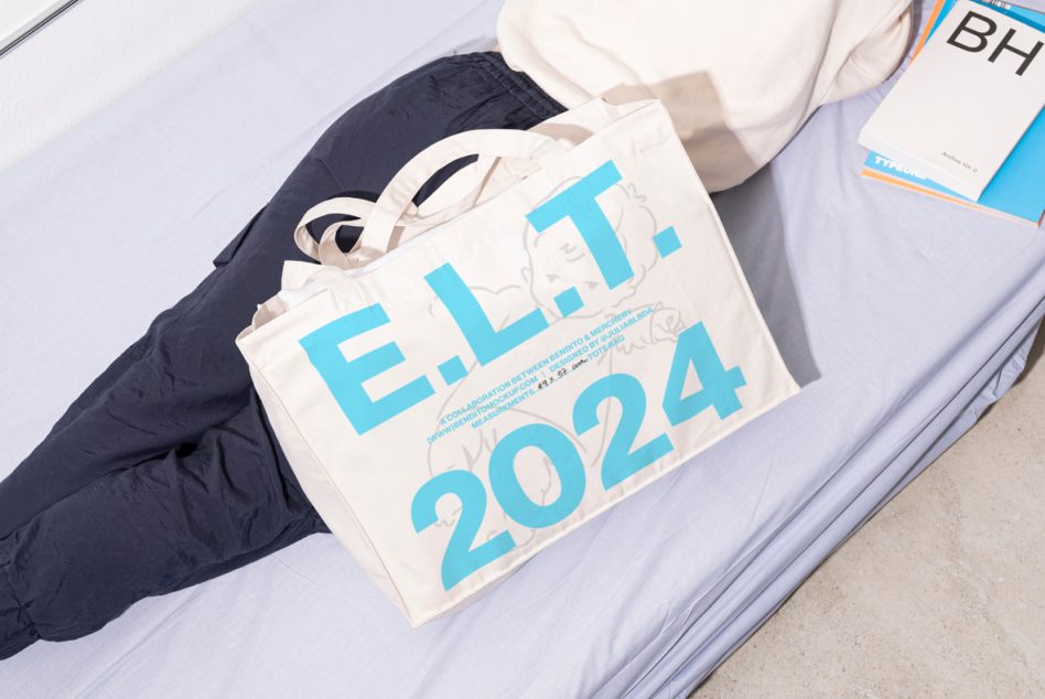 Natural canvas tote bag with cyan blue text reading E.LT 2024 held by person in dark outerwear