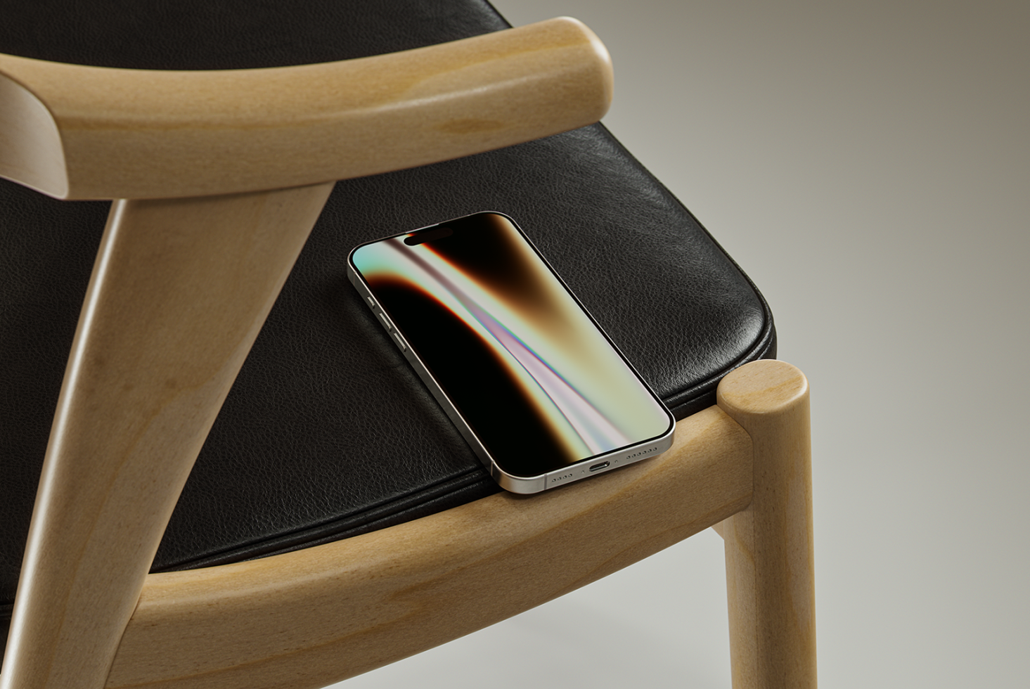 Mobile phone resting on a black leather chair with wooden frame. Perfect for showcasing mobile app mockups or UI designs. Ideal for graphic designers.