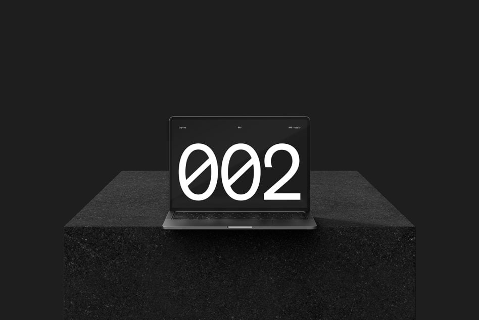 Laptop on concrete table displaying bold 002 typography in center