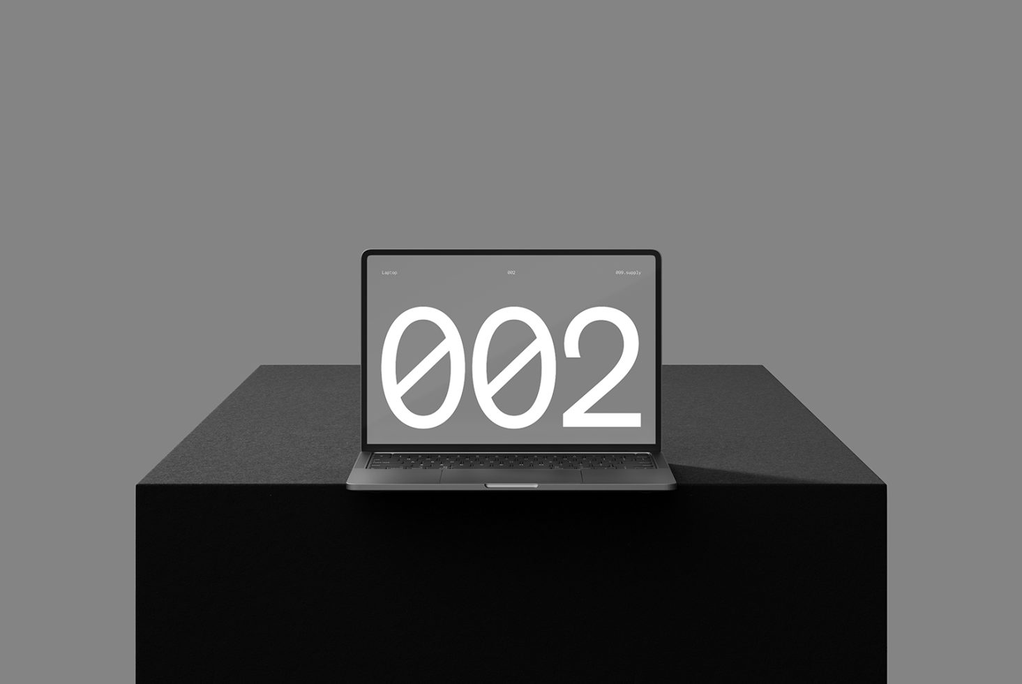 Minimalist laptop mockup on a dark pedestal displaying large number 002 on the screen suitable for digital design assets targeting designers and creatives