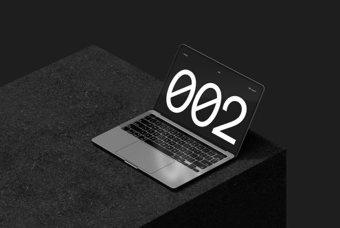 Laptop mockup displaying large bold numbers on a screen positioned on a dark textured surface ideal for showcasing digital designs and presentations