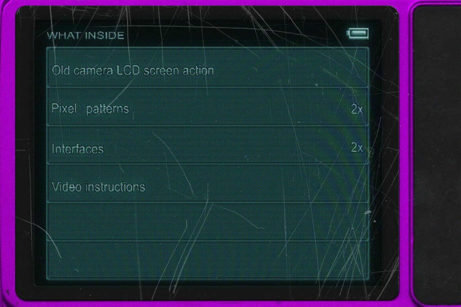 Close-up of an old camera LCD screen showing action menu with pixel patterns interfaces and video instructions. Ideal for graphic design mockups.