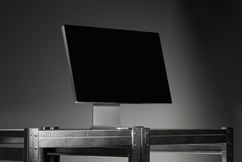 Wide-screen computer monitor mockup on industrial metal desk in a dimly lit studio setting ideal for designers. Keywords: mockup, monitor, design, template.