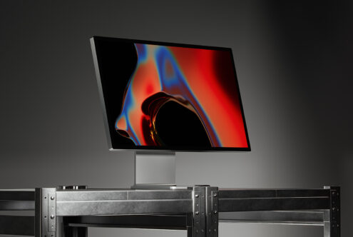 Modern computer monitor with abstract digital art displaying vibrant colors on a metal stand, ideal for graphics design inspiration and tech mockups.