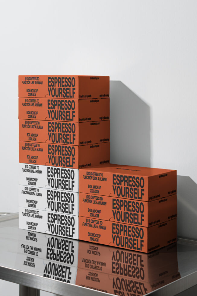 Box mockup on a steel table featuring stacks of orange and white boxes with bold text reading Espresso Yourself. Ideal for packaging design templates.