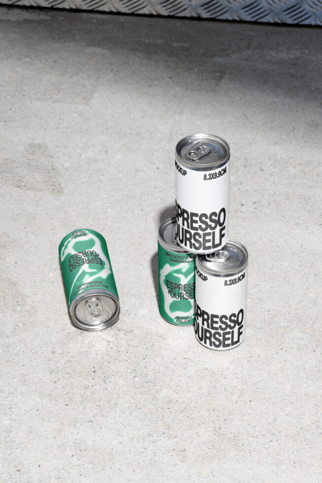 Four aluminum cans on concrete, two white, two green, featuring bold typography. Ideal for product mockups. Keywords: mockup, packaging design, can.