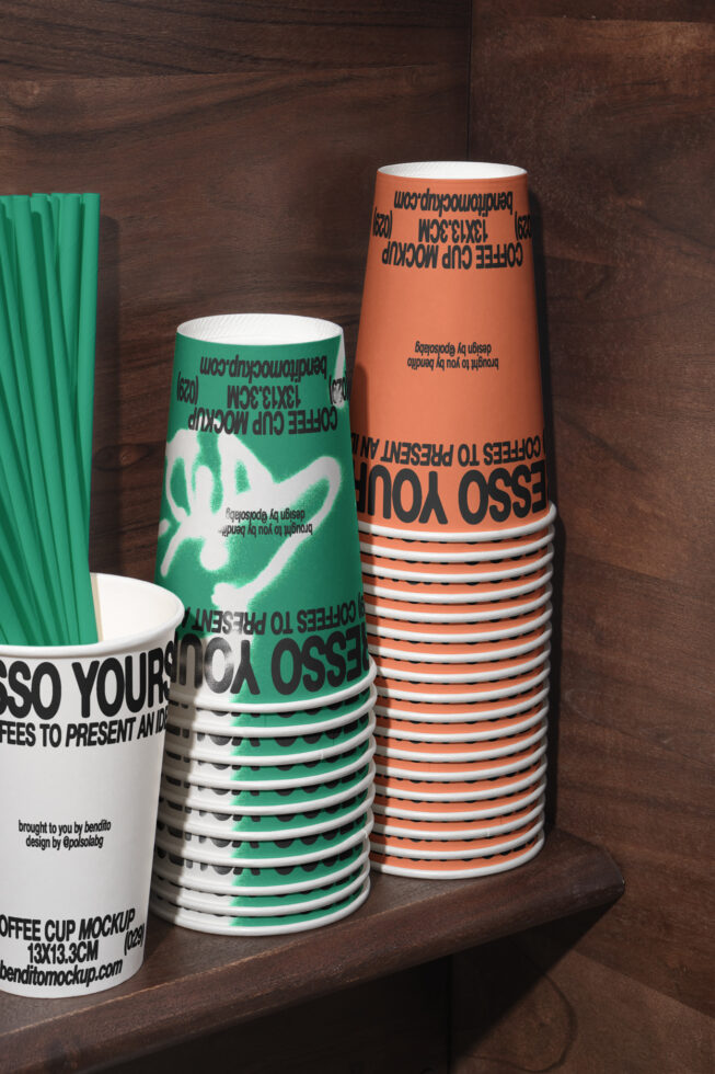 Stacked coffee cup mockup in green and orange with bold typography on a wooden shelf for branding design presentations. Suitable for graphic designers.