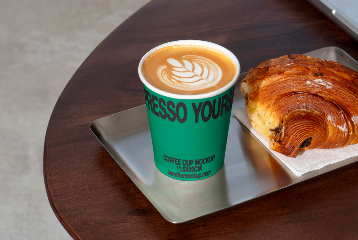 Coffee cup mockup with latte art on wooden table next to a croissant design template for designers. Keywords mockup coffee design template croissant.