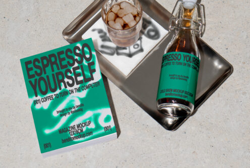 Magazine mockup with bold Espresso Yourself text alongside a cold brew bottle on a tray and glass of iced coffee. Ideal for designers seeking creative graphics.