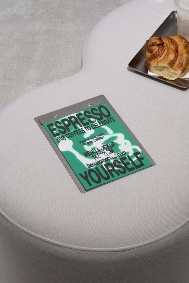 Mockup of a metal clipboard with a vibrant menu design on a neutral fabric seat. Ideal for showcasing graphic templates to designers. Croissant and coffee.