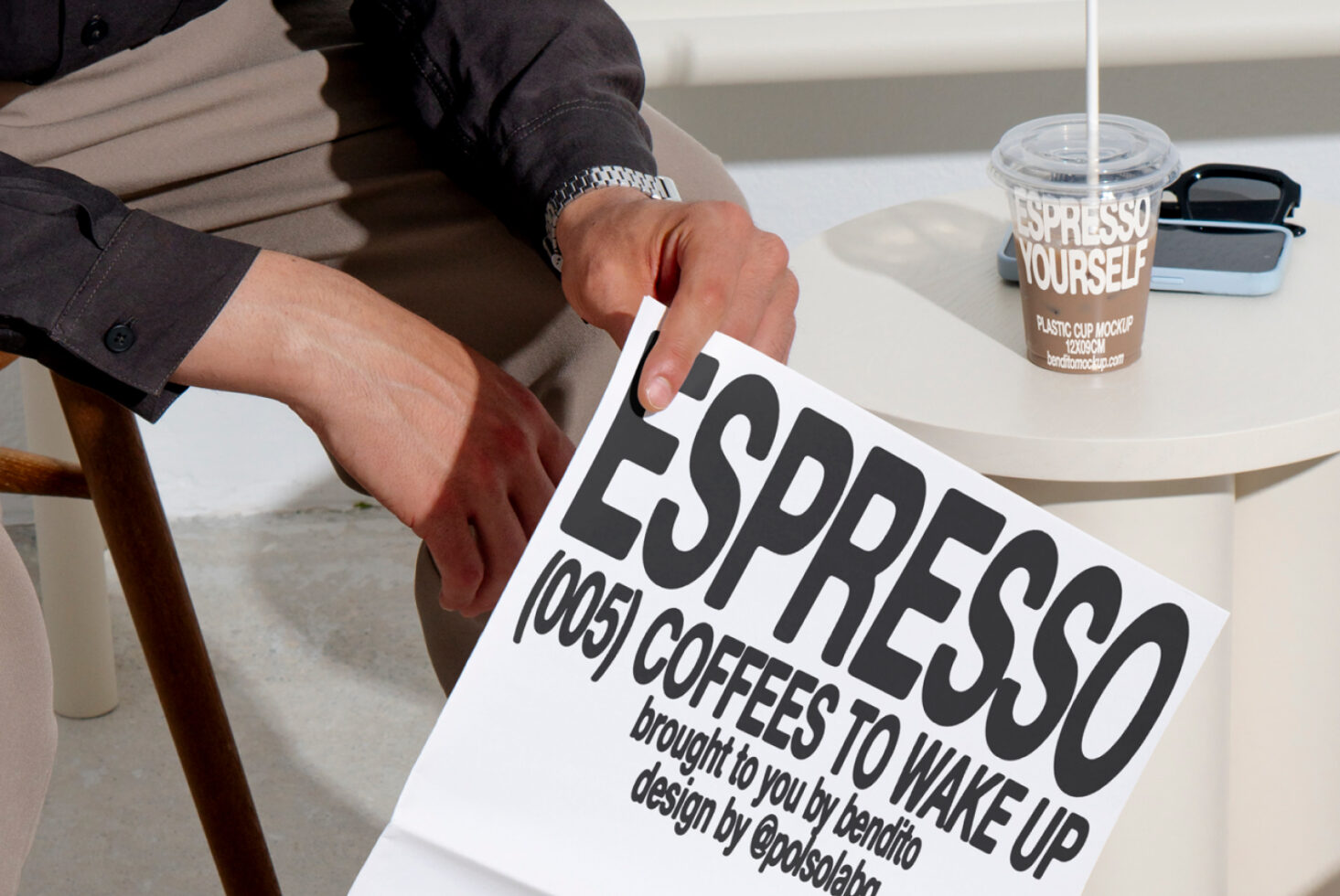 Person holding a poster with bold espresso font design. Table with espresso cup mockup and sunglasses. Ideal for designers seeking modern typography mockups.