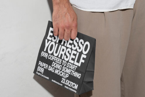 Hand holding a black paper bag with bold text Espresso Yourself showcasing a paper bag mockup design for creative professionals and designers.