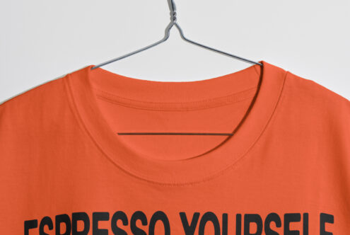 Orange t-shirt with Espresso Yourself design hanging on a metal hanger. Perfect for mockups and graphic design projects. Fashion assets for designers.