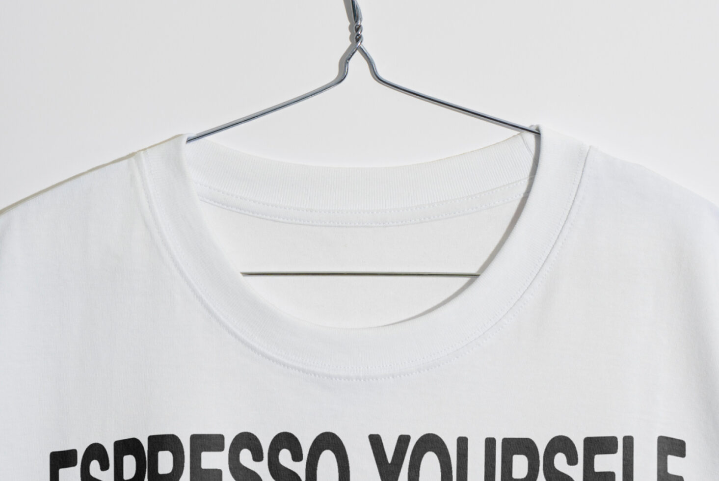 White T-shirt mockup on hanger with Espresso Yourself text. Ideal for fashion designers or graphic designers. Minimalist apparel template for creativity.