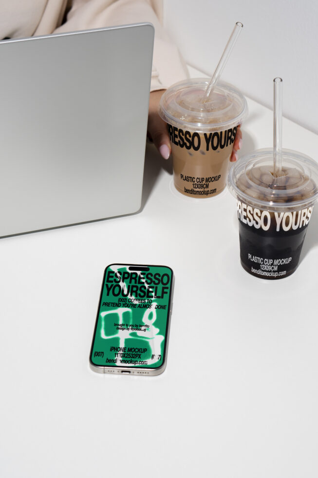 Laptop and smartphone on desk with plastic coffee cup mockups. Ideal for showcasing design templates and branding concepts for graphic designers.