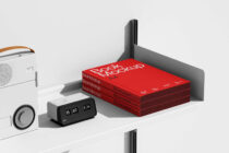 Red A4 book mockups stacked on shelf display with speaker beside