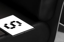 Tablet resting on black leather chair displaying dots in circular formation