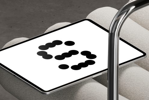 Tablet displaying black dot pattern graphic on a modern chair. Ideal for digital design projects. Keywords: mockup, graphic design, tablet, pattern.