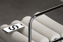 Smartphone mockup on cream pillow with chrome stand, black dots on screen