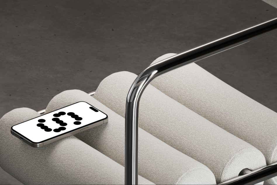 Smartphone mockup on cream pillow with chrome stand, black dots on screen