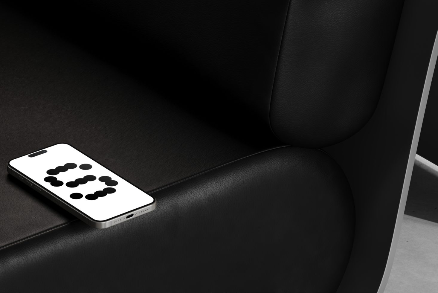 Smartphone mockup on black leather couch showcasing minimalistic design. Perfect for designers seeking realistic device presentations in advertising projects.