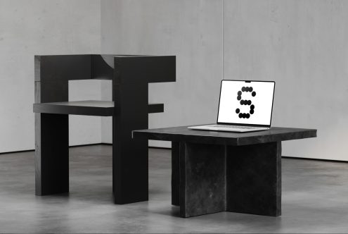 Minimalist black chair and table with a laptop displaying a dot letter S. Modern furniture design mockup in a concrete room. Interior design assets.