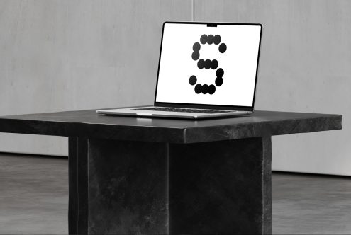 Laptop on dark table showing graphic letter S in dots. Ideal for designers seeking unique font mockups or digital assets. Studio background.