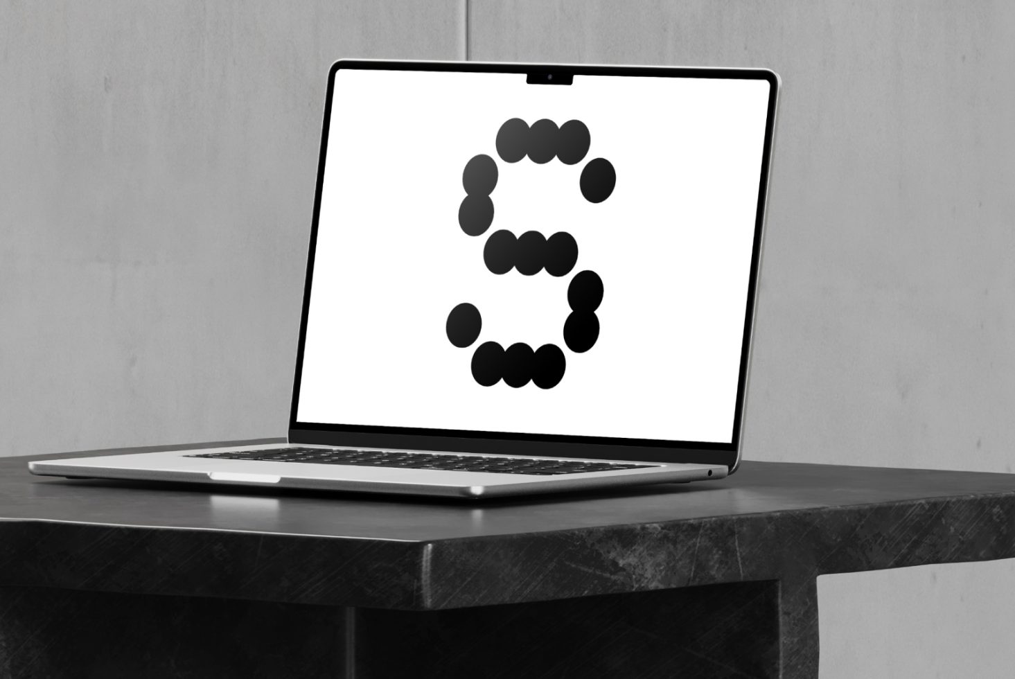 Laptop on a dark table displays a modern abstract font design with circular elements forming the letter S suitable for graphic design projects.