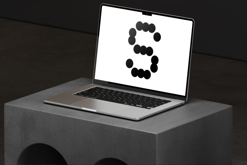 Laptop mockup on concrete block with modern letter S design on screen perfect for showcasing digital designs and templates for graphic designers.