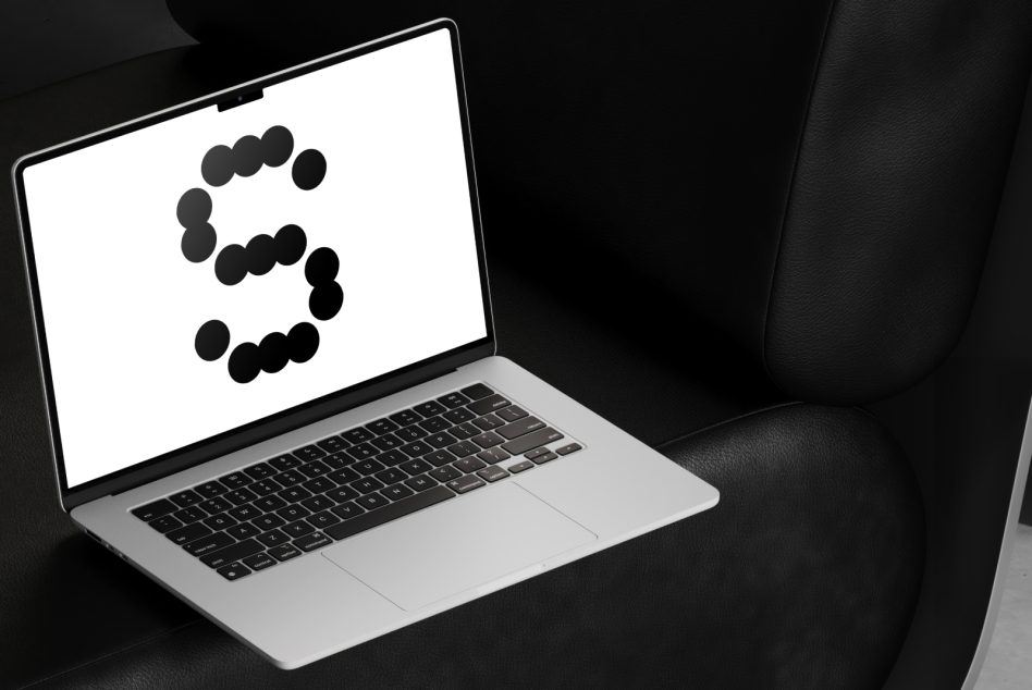 Laptop on black couch displaying creative font design with polka dot letter S. Ideal for designers seeking unique typographic assets and mockup templates.