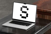 MacBook laptop displaying black circles forming number 5 design
