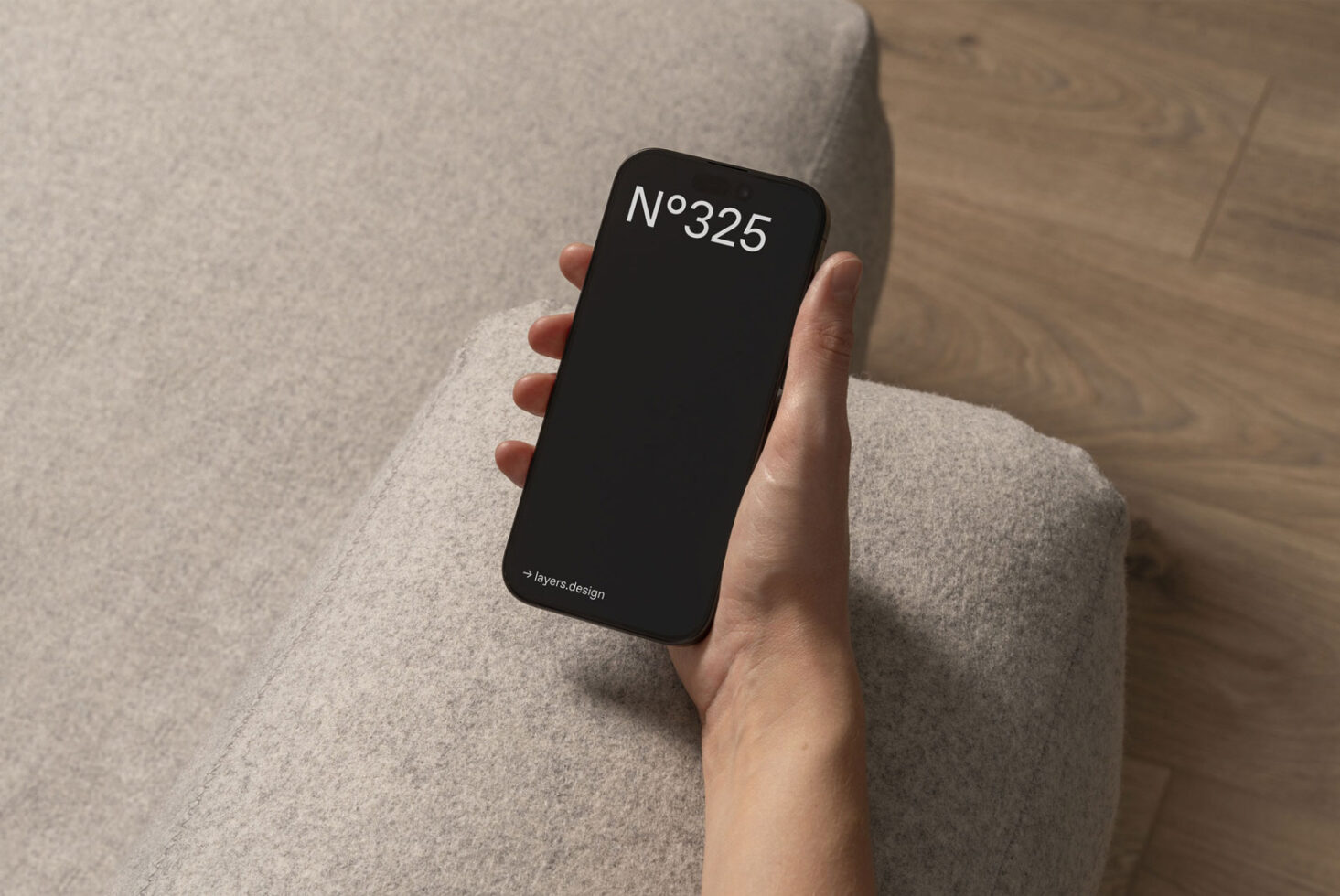 Hand holding smartphone with black screen mockup on textured gray sofa. Ideal for showcasing UI design and app interfaces. Perfect for designer use.