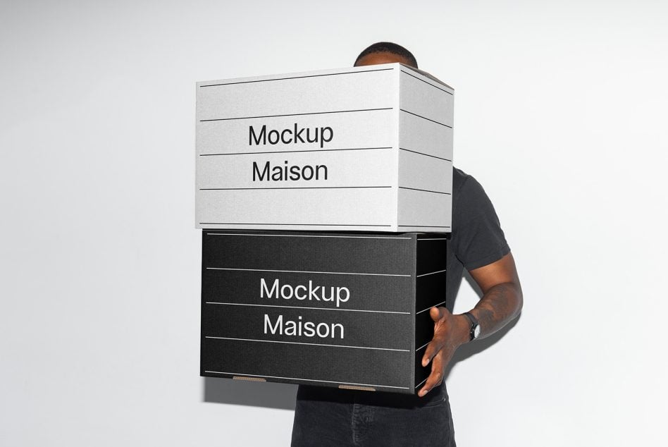 Man carrying stacked black over white packaging boxes with horizontal lines
