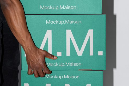 Stack of green Mockup.Maison boxes with a hand lifting one, suitable for packaging mockup. Ideal for designers' digital assets.