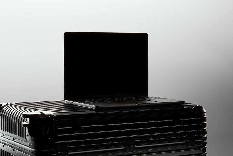 Sleek black laptop on a large textured suitcase with a minimalist backdrop perfect for product mockups digital presentations design showcases sleek tech