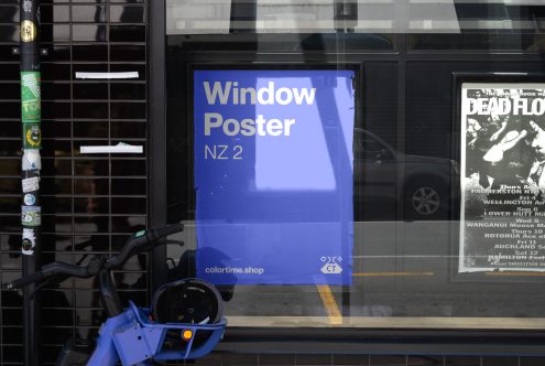 Urban window poster mockup in blue with text NZ 2 displayed next to storefront. Ideal for showcasing design templates and advertising graphics for designers.