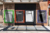 Four colorful poster frames in neon green, orange, white, blue mounted on brick storefront