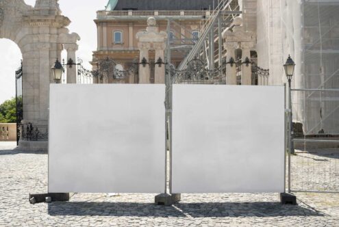 Outdoor banner mockup in historical setting with blank white canvases framed by stone pillars suitable for design presentations and advertising visuals.