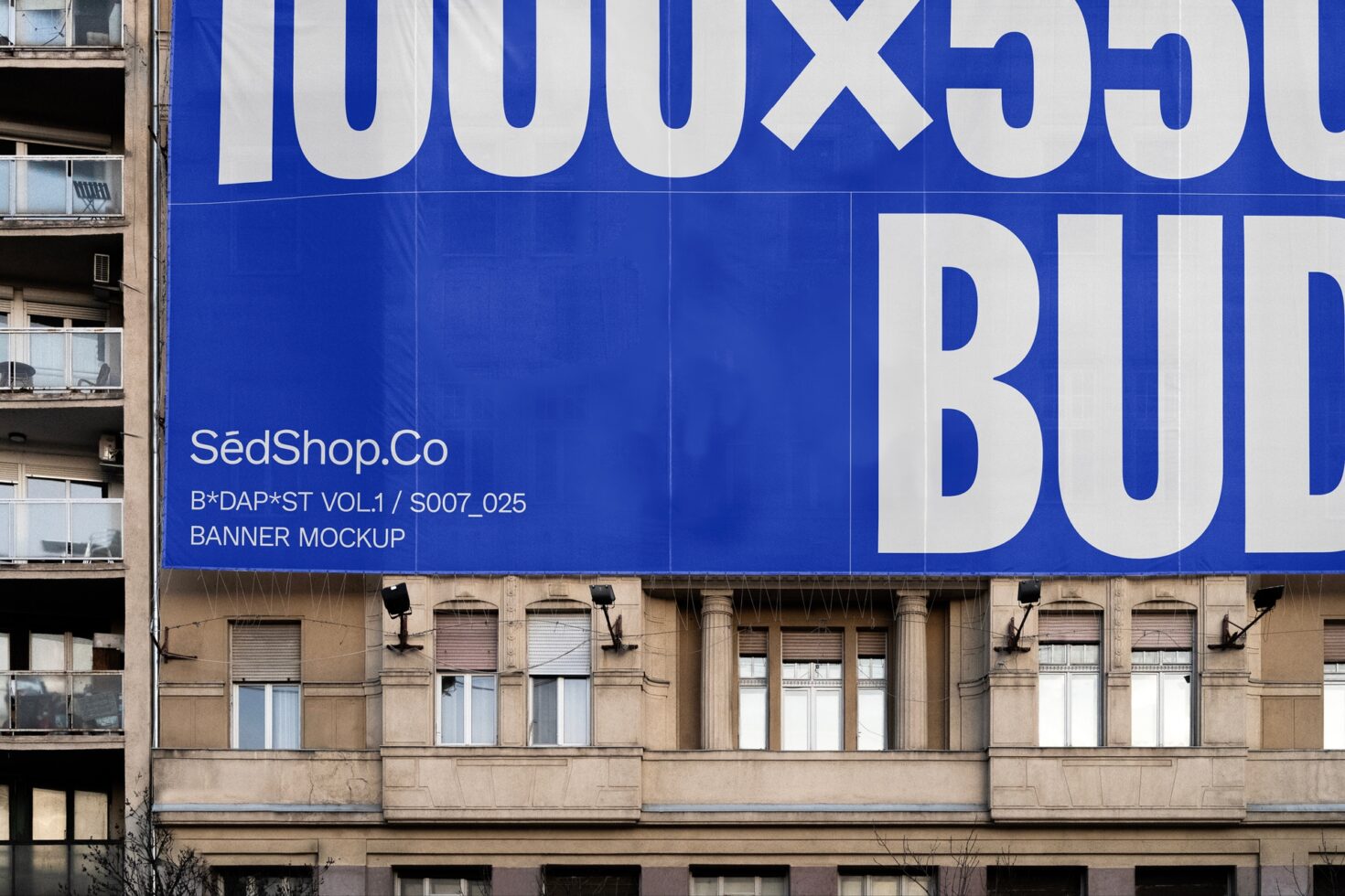 Large blue banner mockup on building facade; urban advertising design; graphic template for creatives; street view with customizable format; SedShop Co