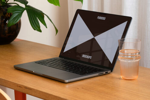 Laptop mockup on a wooden desk with a glass of water and a plant nearby ideal for digital design presentations focus on modern layouts for designers