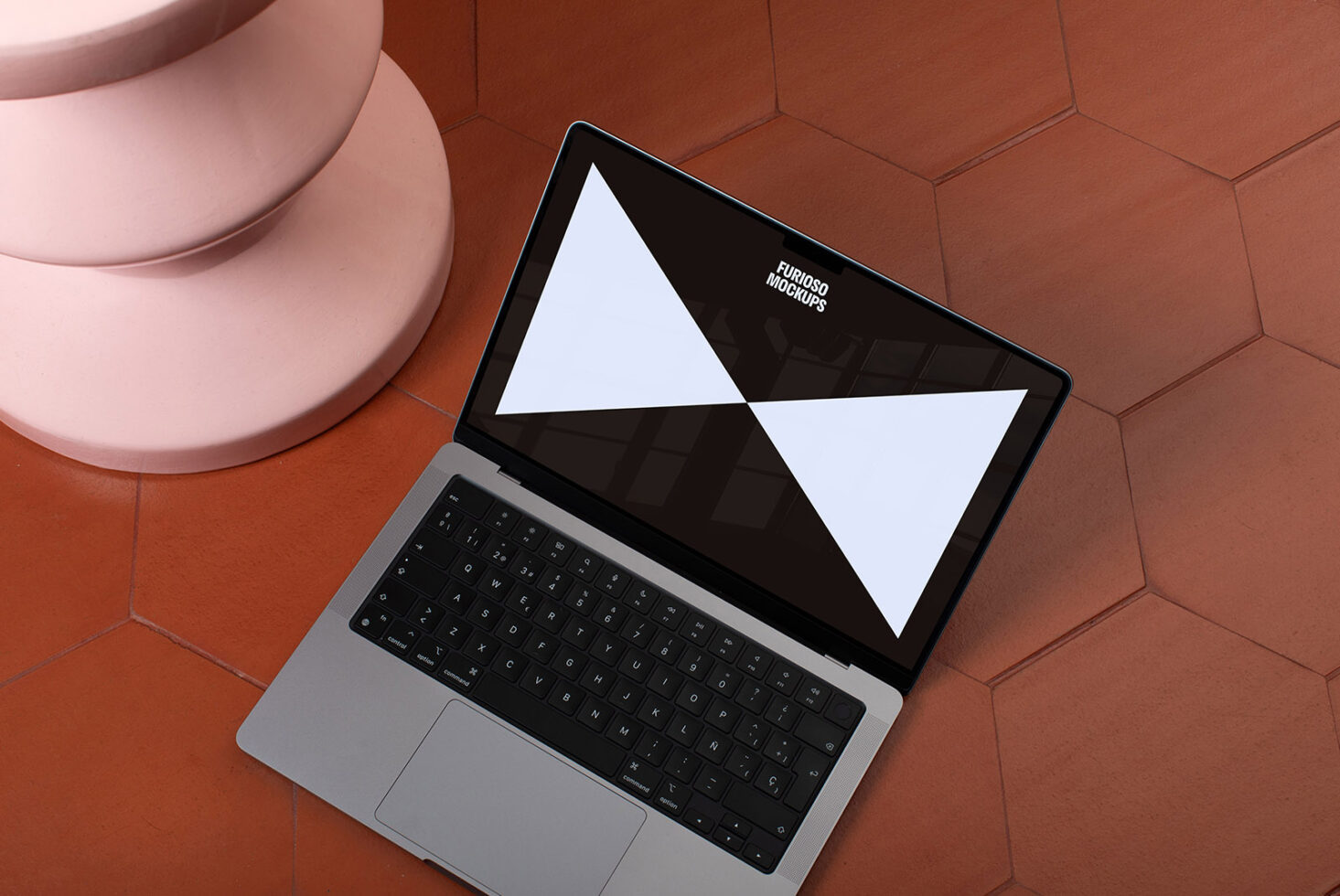 Laptop mockup on hexagonal tile floor beside pink pedestal. Ideal for showcasing digital designs. Keywords: mockup design laptop digital assets.