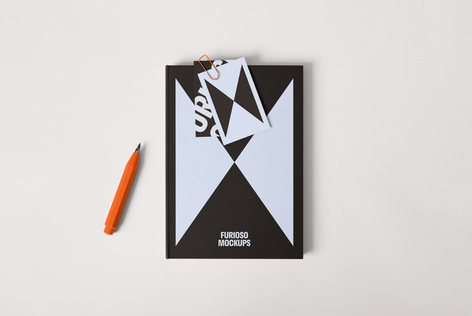 Black notebook with geometric design for mockup. Includes orange pen and paperclip; perfect for graphic design projects and templates. Creative resources.