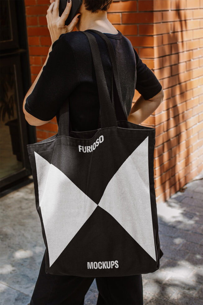 Designer carries black tote bag with geometric design suitable for mockups. Ideal for graphic design, branding, and showcasing creative projects.