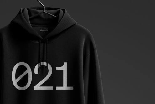 Black hoodie mockup hanging on a hanger against a dark background. Minimalist design with bold typography '021'. Ideal for apparel designers and graphic projects.