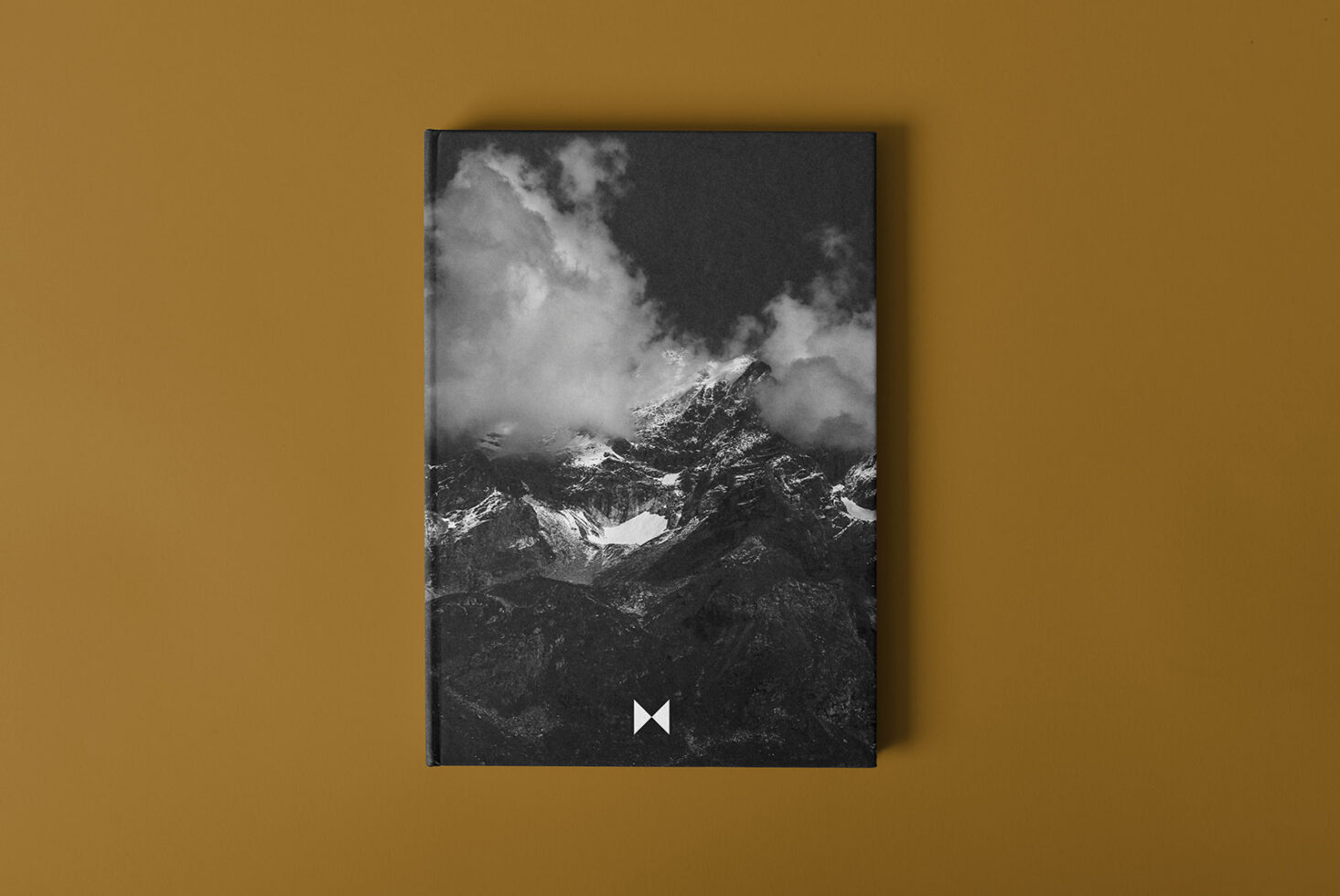 Hardcover book mockup with a black and white mountain photo on a brown background. Ideal for showcasing graphic design projects to designers.