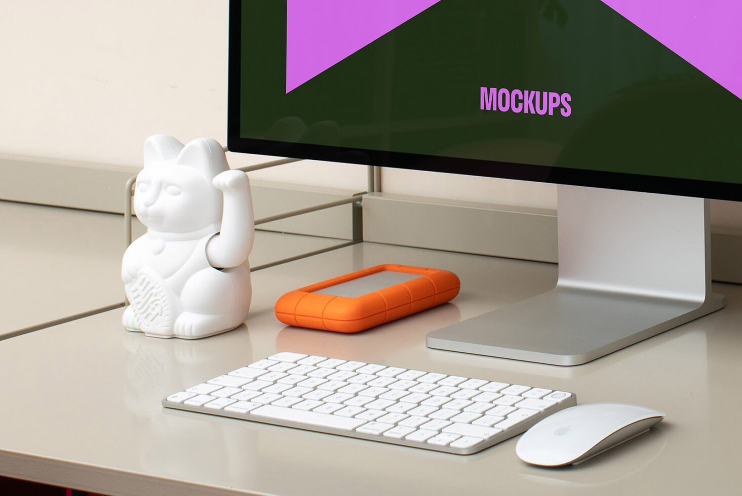 Workspace with desktop screen displaying Mockups keyword an orange hard drive mouse keyboard and a white cat figurine perfect for designers SEO friendly