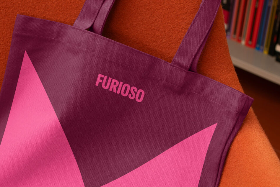 Purple tote bag with pink geometric design on orange background suitable for mockups or graphic design projects. Fashion accessory, branding concept.