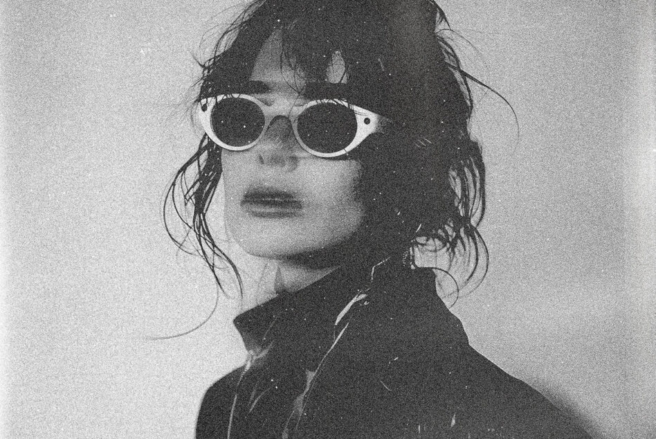 Monochrome gritty portrait of person wearing sunglasses dark hair styled fashion photography suitable for graphic design texture mockups and templates.