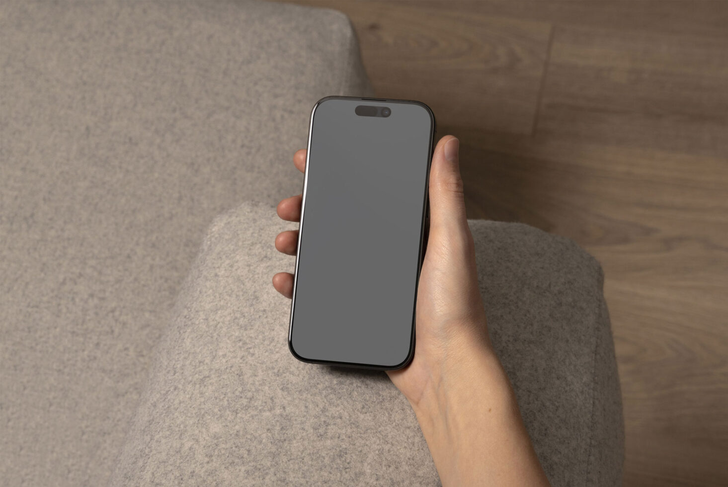 Phone mockup in hand on gray fabric and wooden floor background ideal for showcasing app designs digital assets for designers and templates.