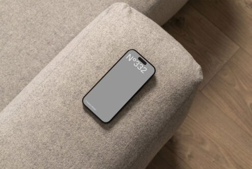 Minimalist smartphone mockup featuring a sleek device on a modern gray fabric sofa. Ideal for digital presentations and design templates.